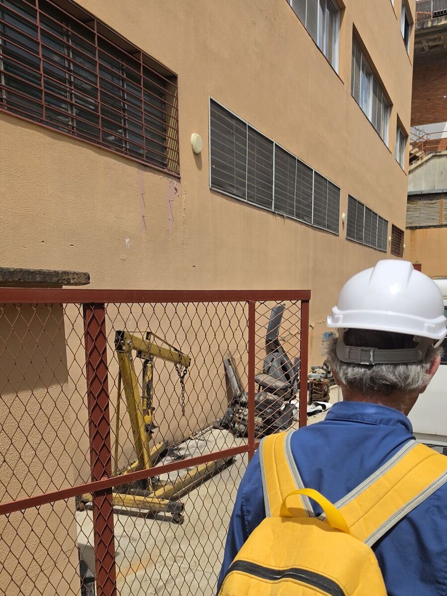 Inspector de Corporación 3JC con casco y chaleco reflectivo evaluando la fachada de un edificio en Caracas